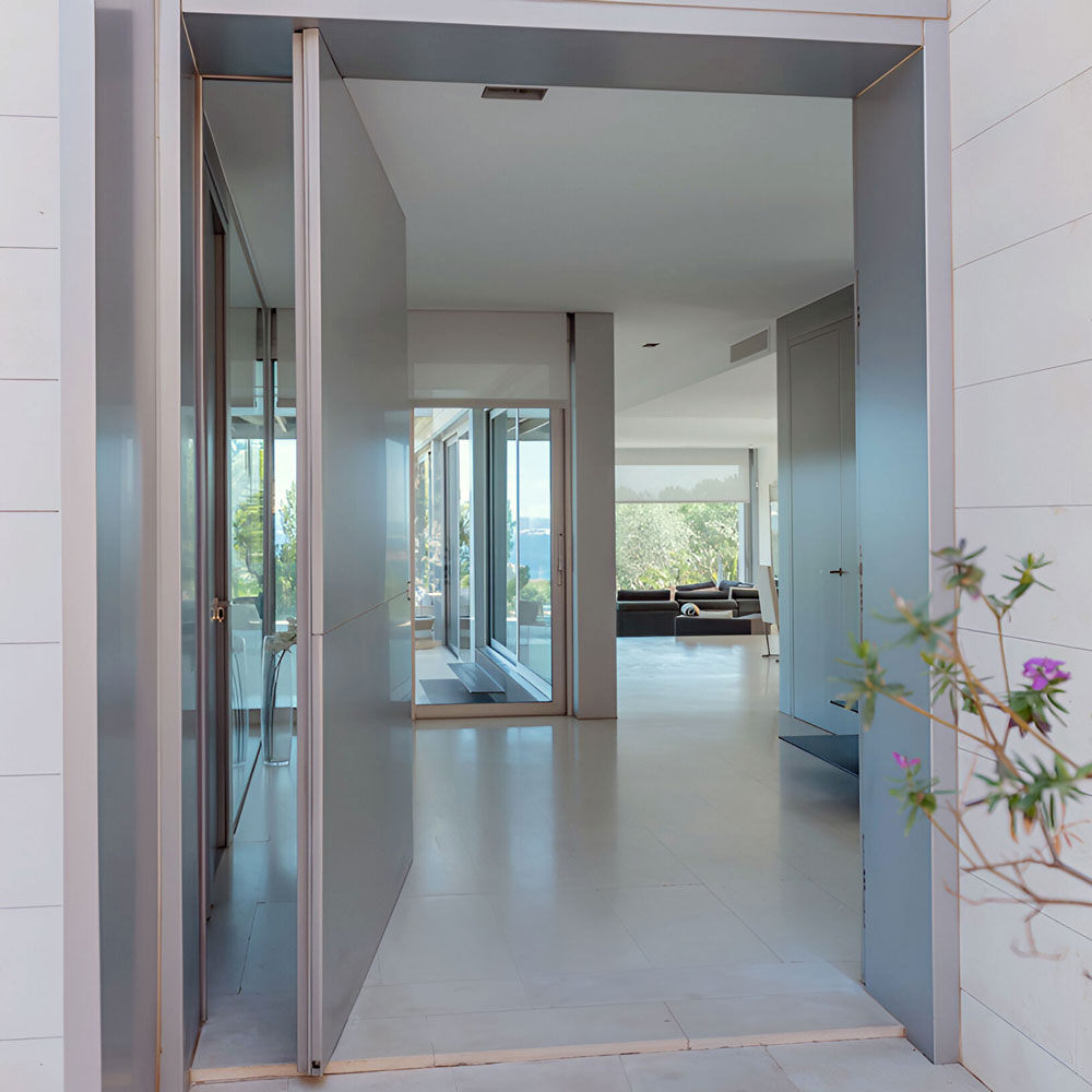 Moderner Eingangsbereich mit geöffneter Tür und Blick ins lichtdurchflutete Innere einer Villa in Bendinat auf Mallorca