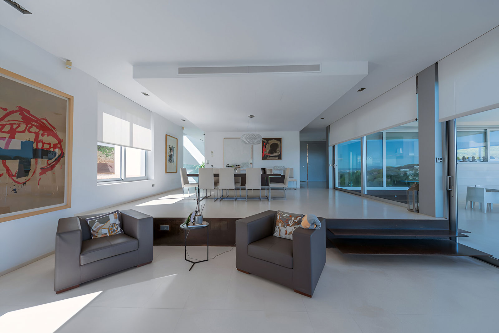 Offener Wohnbereich mit Designmöbeln und großen Fensterflächen in moderner Villa in Bendinat auf Mallorca